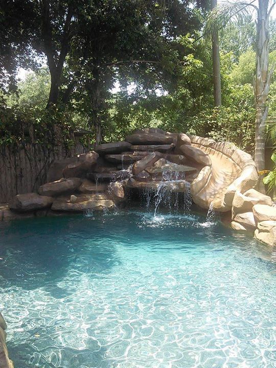 an outdoor pool with waterfall and rocks