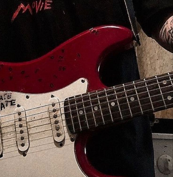 a red electric guitar sitting on top of a floor