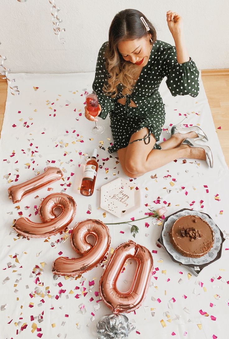 a woman sitting on the floor with balloons and confetti in front of her