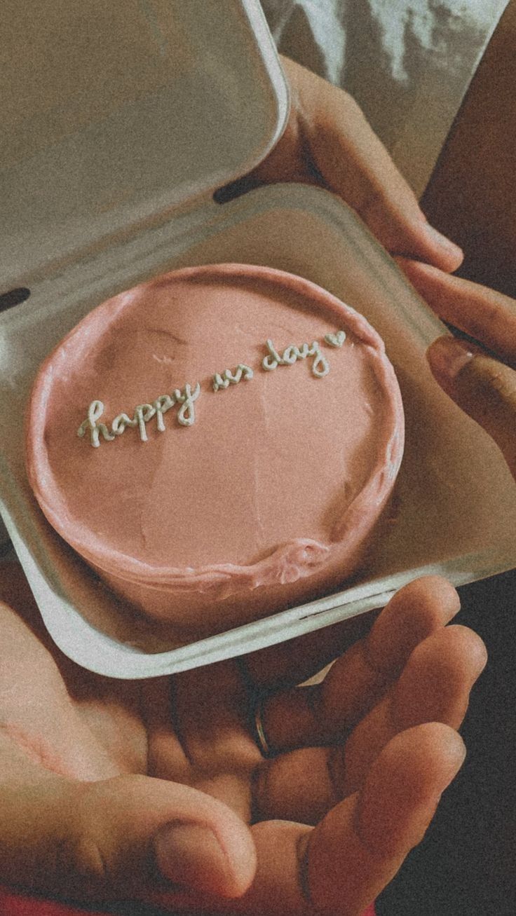 a person holding a cake in their hands with the words happy on it written on it