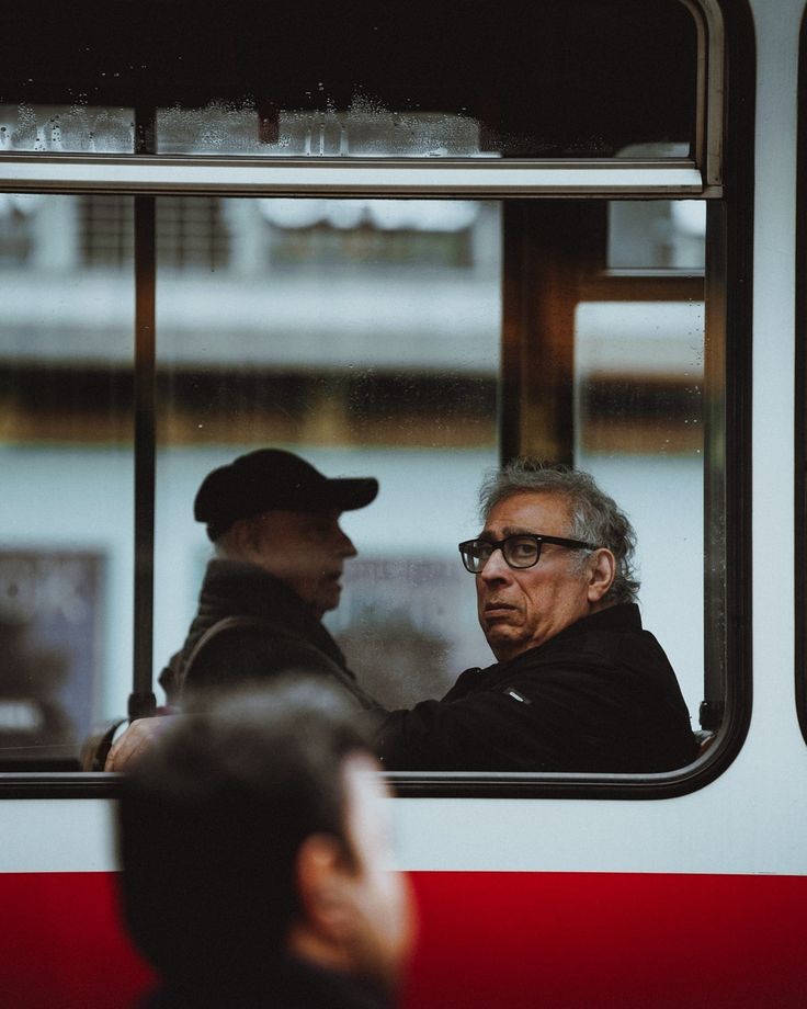 an older man is talking to another old man on the subway train, looking out the window