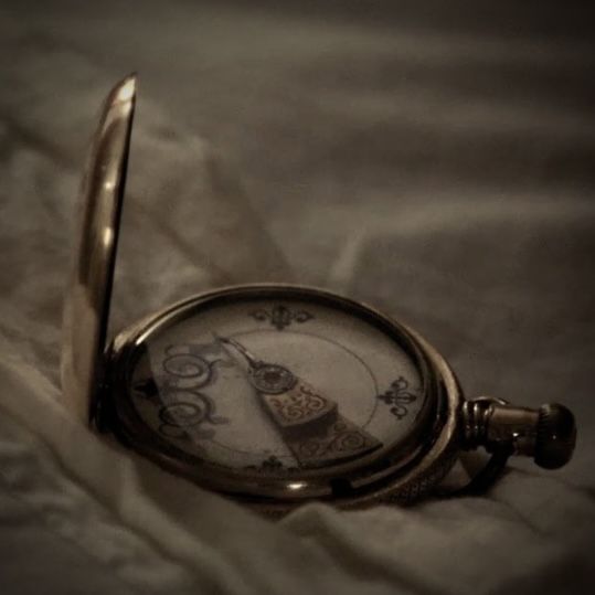 a close up of a pocket watch on a bed