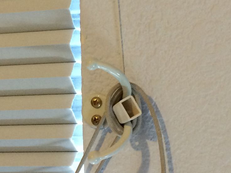 a pair of scissors is hooked up to the side of a window with white blinds