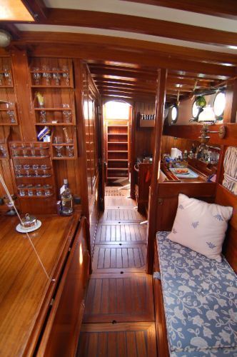 the inside of a boat with wood flooring and wooden shelves filled with glassware