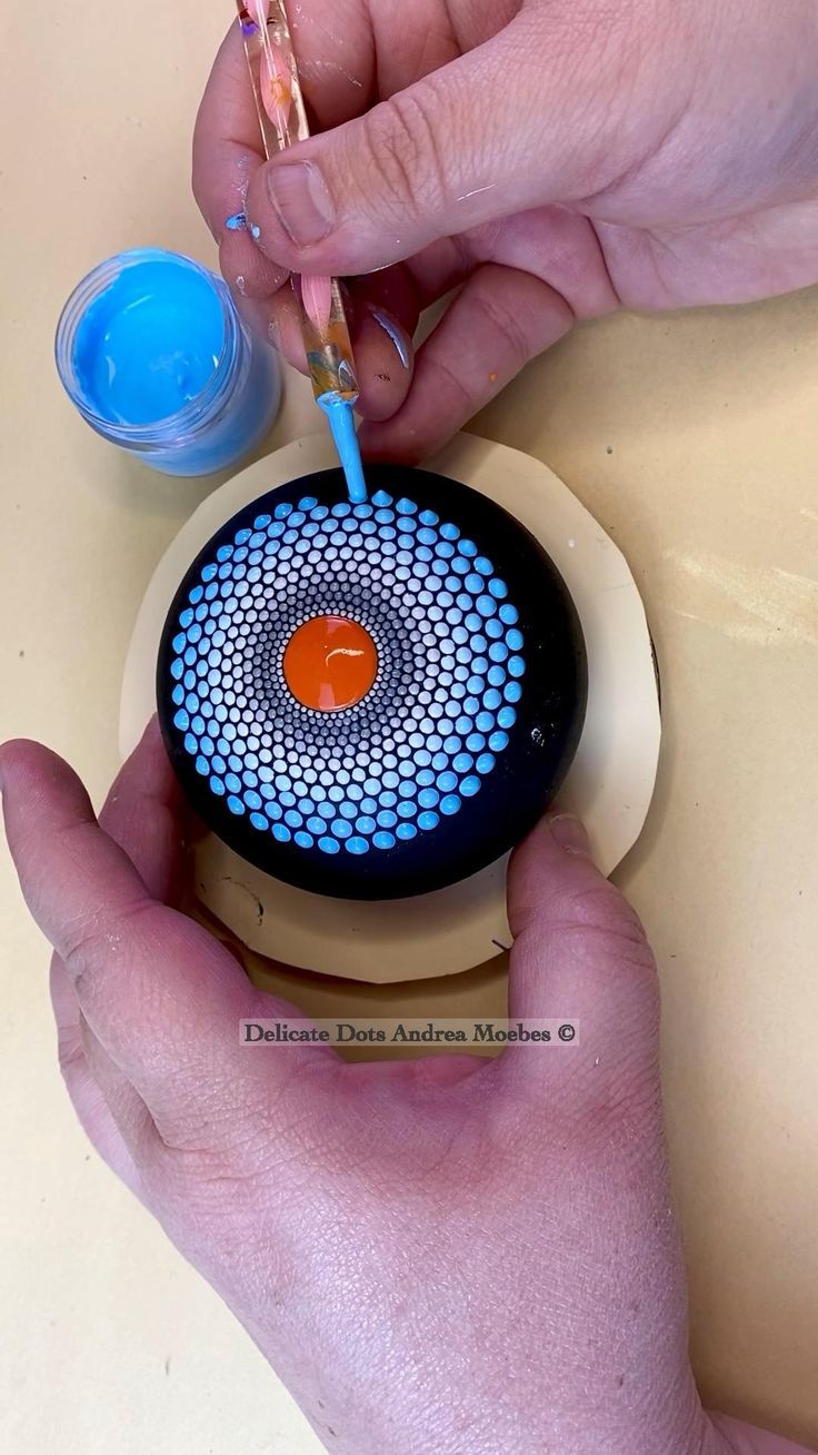 a person is using a toothbrush to brush the top of a blue and orange object