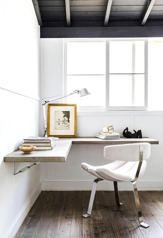 a white chair sitting in front of a window next to a desk