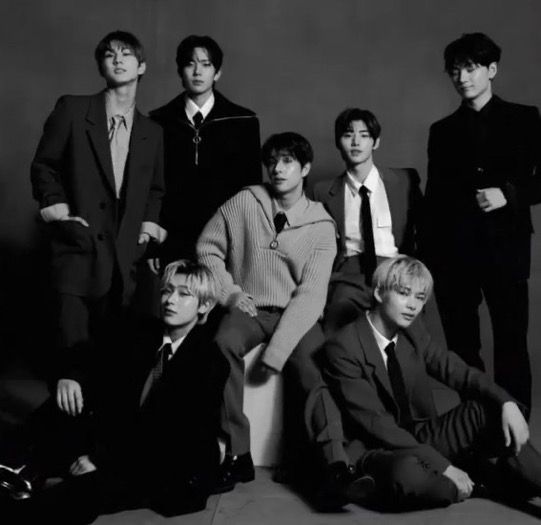 black and white photograph of young men in suits posing for a group photo with one sitting on the floor