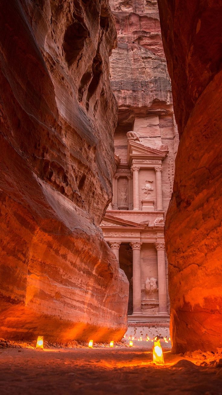 candles are lit in front of the entrance to a building carved out of red rocks