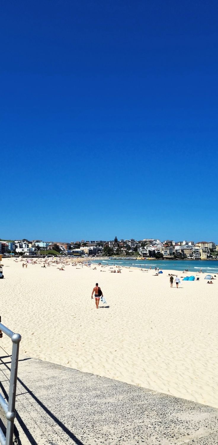 people are walking on the beach and in the water