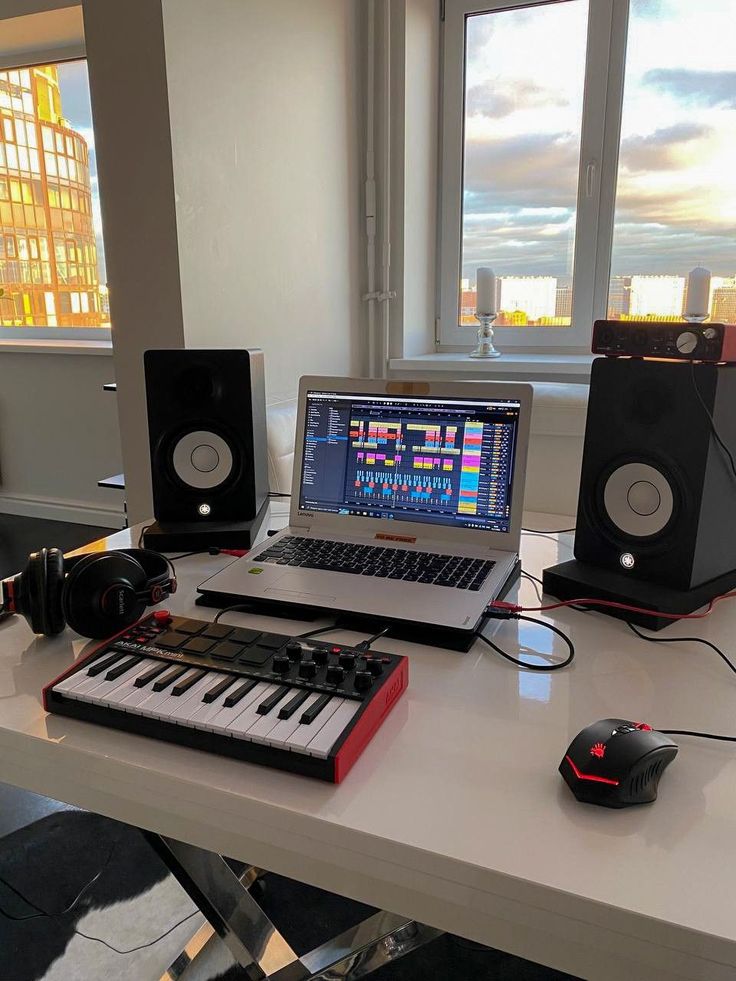 a laptop computer sitting on top of a desk next to a keyboard and headphones