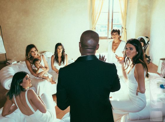 a man standing in front of a group of women sitting on top of a bed