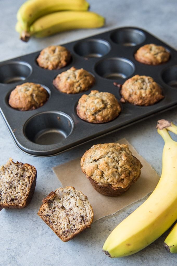 muffins and bananas sitting on a table next to a muffin tray with muffins in it