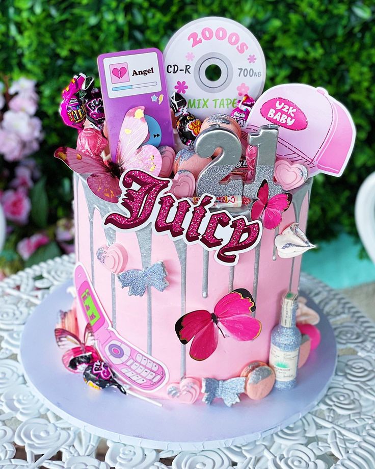 a pink birthday cake with the word juicy on it and lots of stuff around it