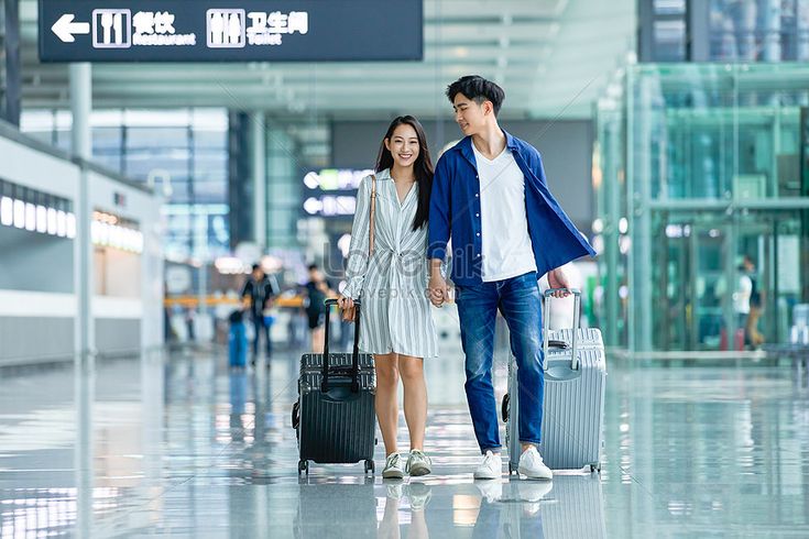 a man and woman are walking through an airport with their suitcases in hand while holding hands