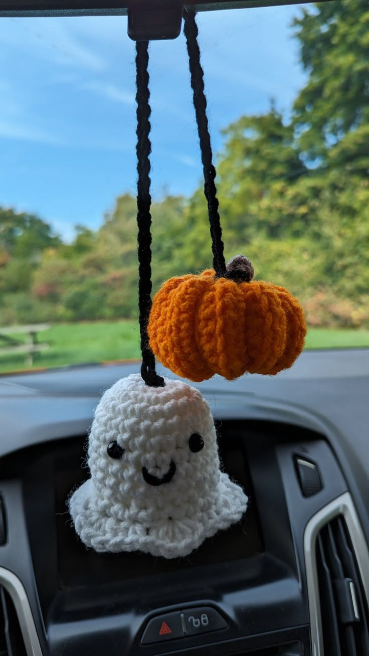 a car dashboard with two crocheted pumpkins hanging from it's hooks