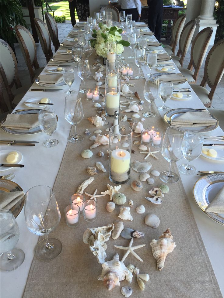 a long table is set with candles and seashells