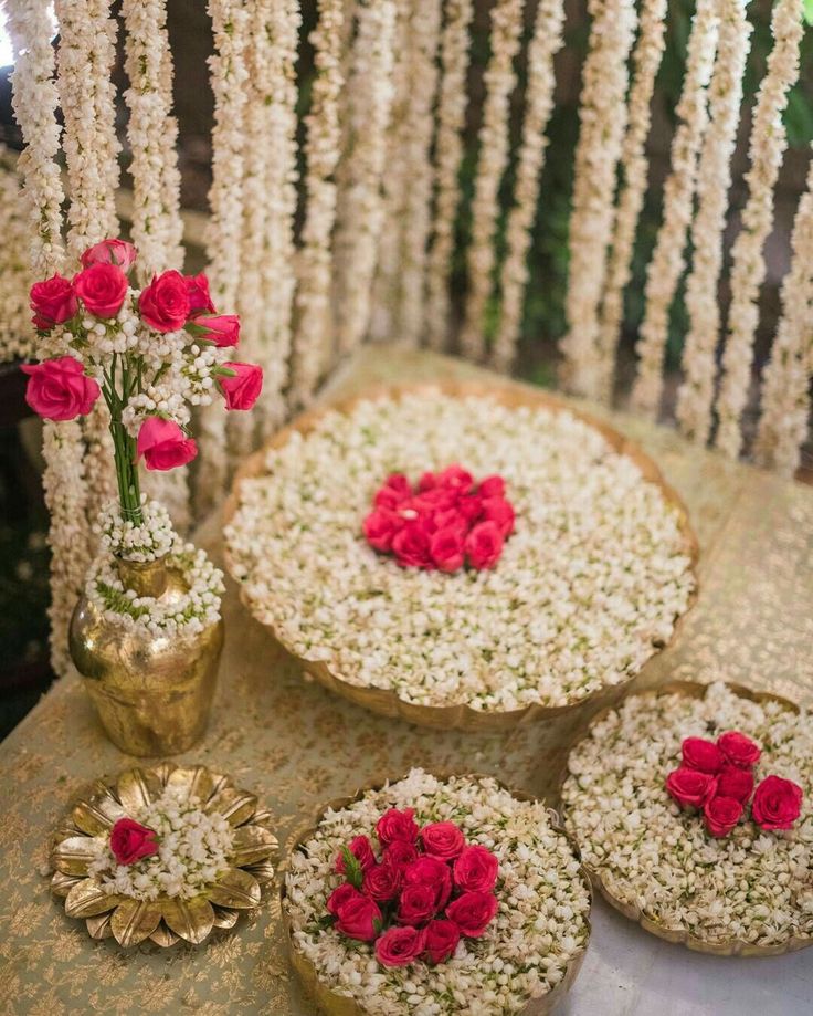 a table topped with lots of pies covered in flowers next to a vase filled with red roses