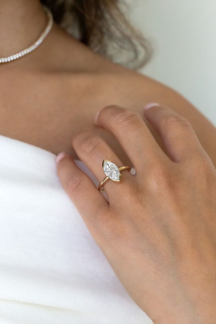 a woman's hand wearing a gold ring with a pear shaped diamond on it