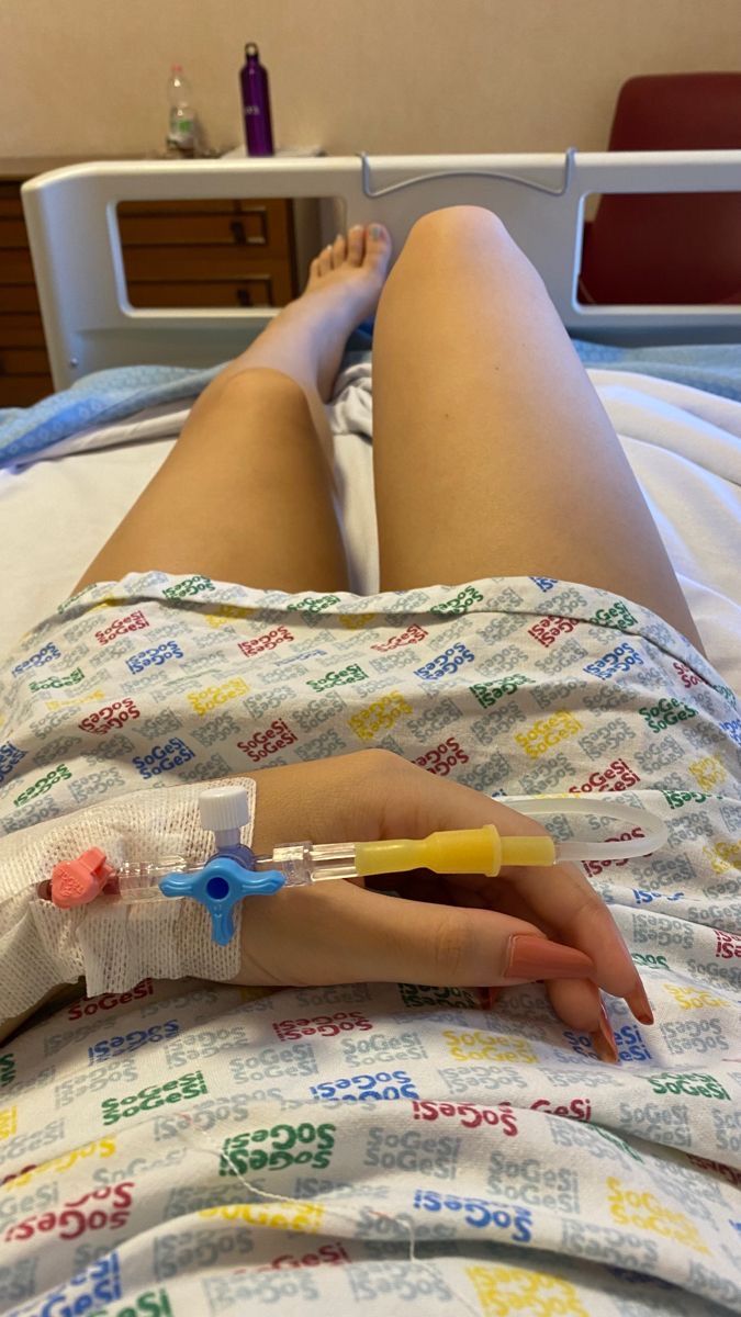 a person laying in a hospital bed with an iv tube attached to their arm and hand