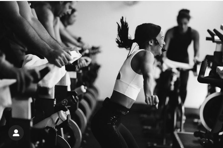 a group of people riding stationary bikes in a spinning room with one person on the bike