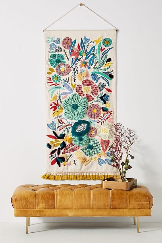 a wooden bench with a tapestry hanging on it's wall next to a potted plant