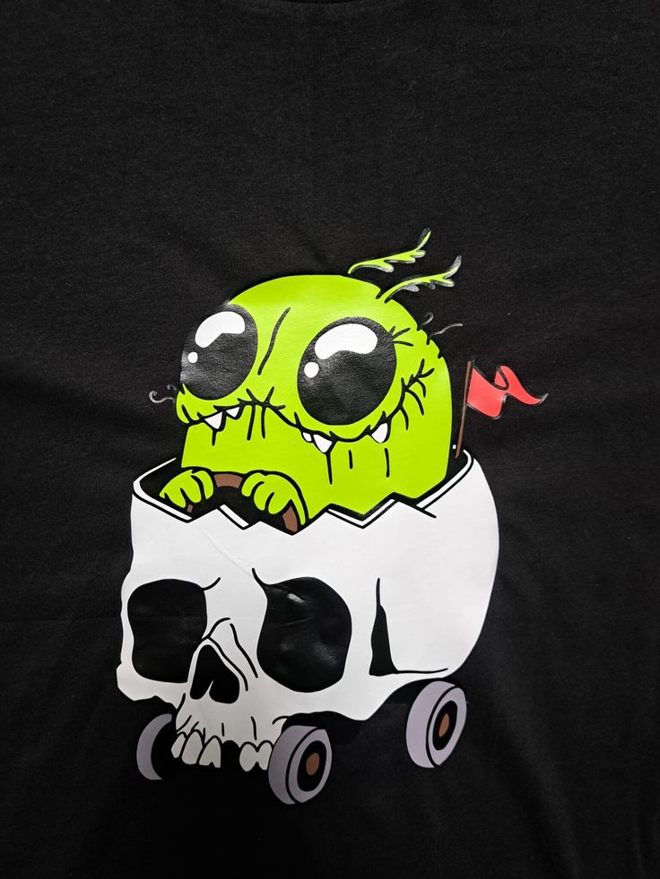 a black t - shirt with a green monster in a skull bowl