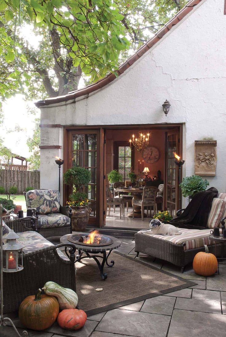 an outdoor living area with wicker furniture and pumpkins on the ground in front of it