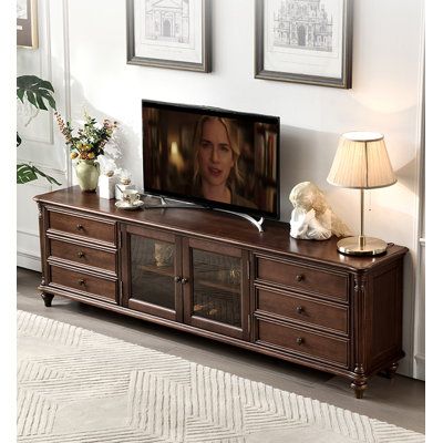 a tv is sitting on top of a wooden entertainment center in a room with two framed pictures above it