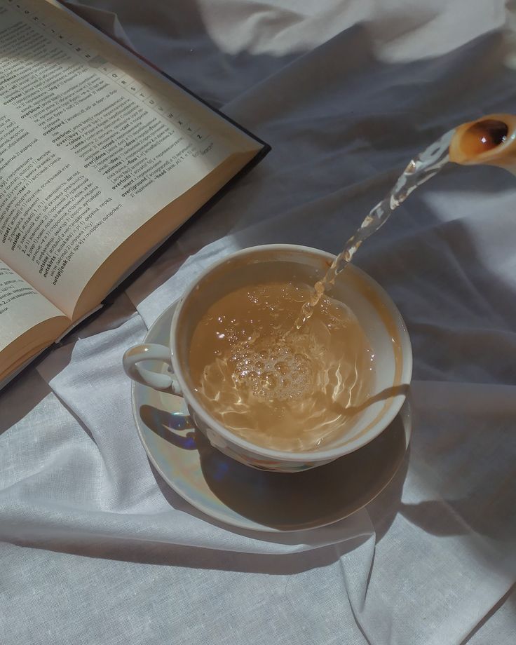 an open book is next to a cup of tea