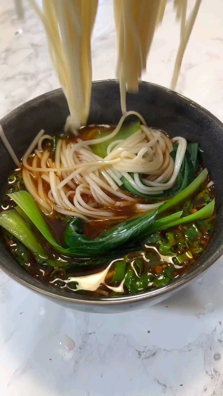 noodles and vegetables being cooked in a wok