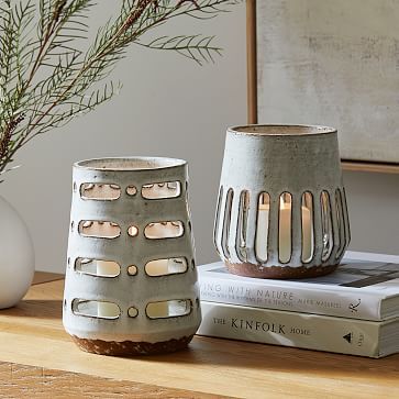 two vases sitting on top of a wooden table next to books and a plant