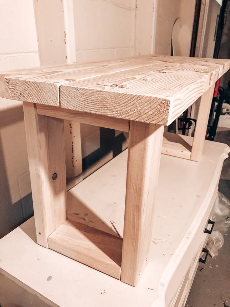 a wooden table sitting on top of a piece of wood in a room next to a wall