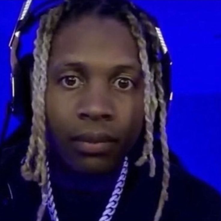 a man with dreadlocks on his head looking at the camera in front of a blue background