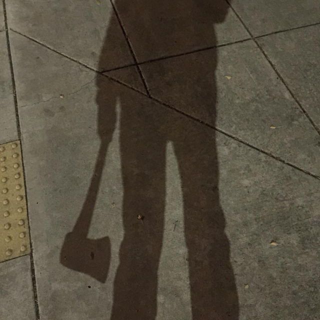 the shadow of a person holding an umbrella over their head while standing on a sidewalk