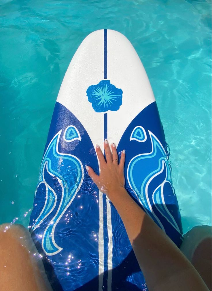 a person is sitting on a surfboard in the water with their hand on it