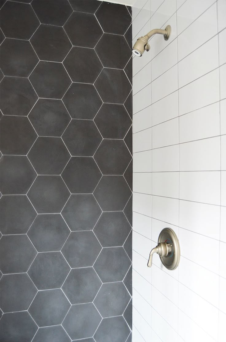 a bathroom shower with hexagonal tiles on the wall, and a metal faucet