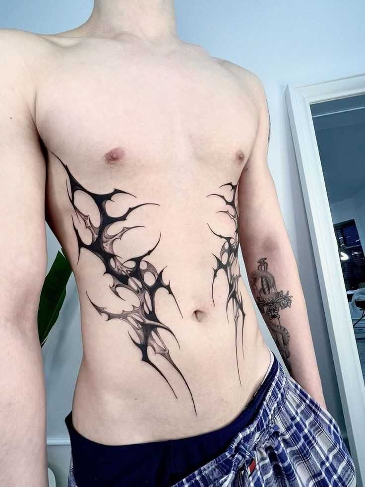 a man with no shirt has his stomach covered in black ink