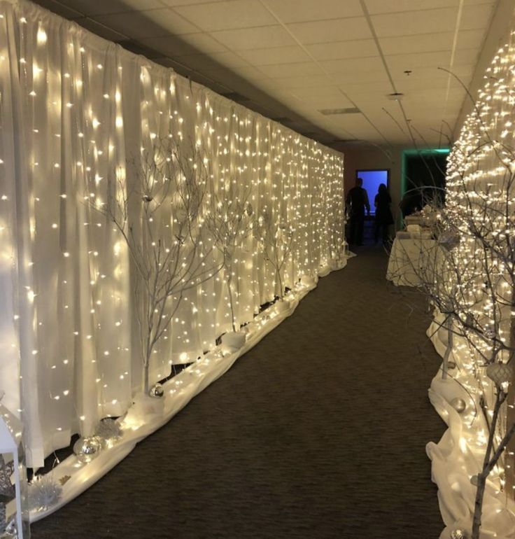 the hallway is decorated with white lights and snow - covered trees, while people are standing in the distance