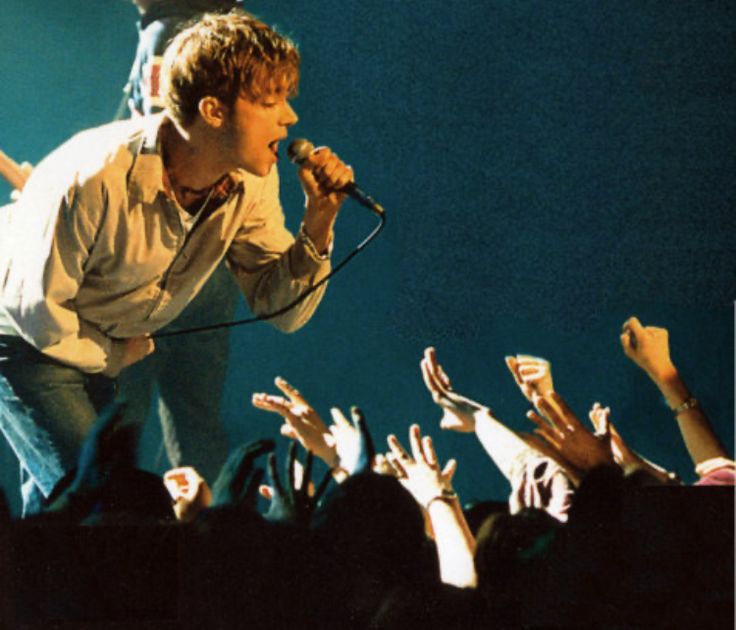 a man standing on top of a stage holding a microphone in front of a crowd