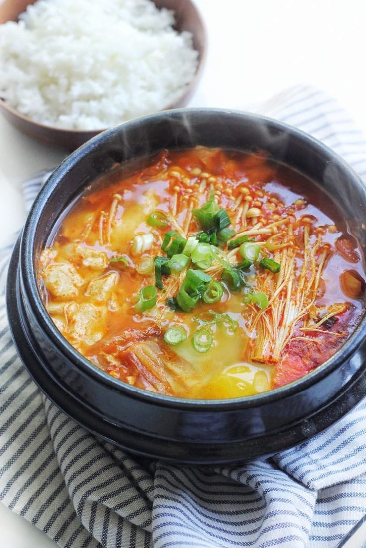 a black bowl filled with soup next to rice