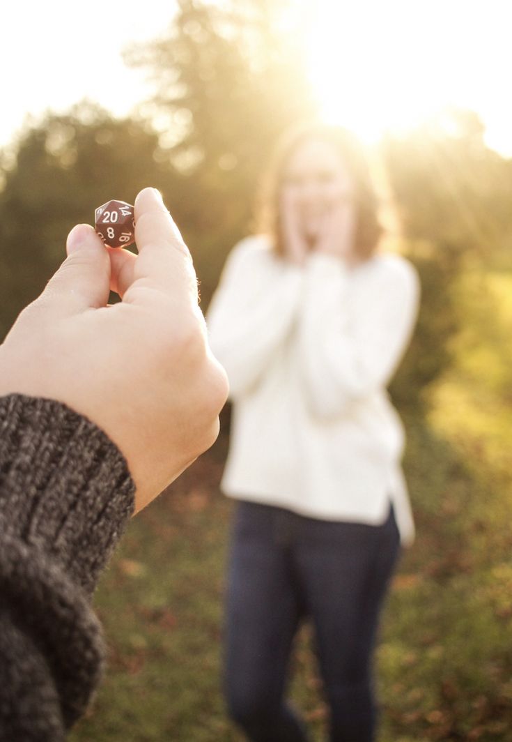 a person holding a dice in their hand while standing next to another person on the grass