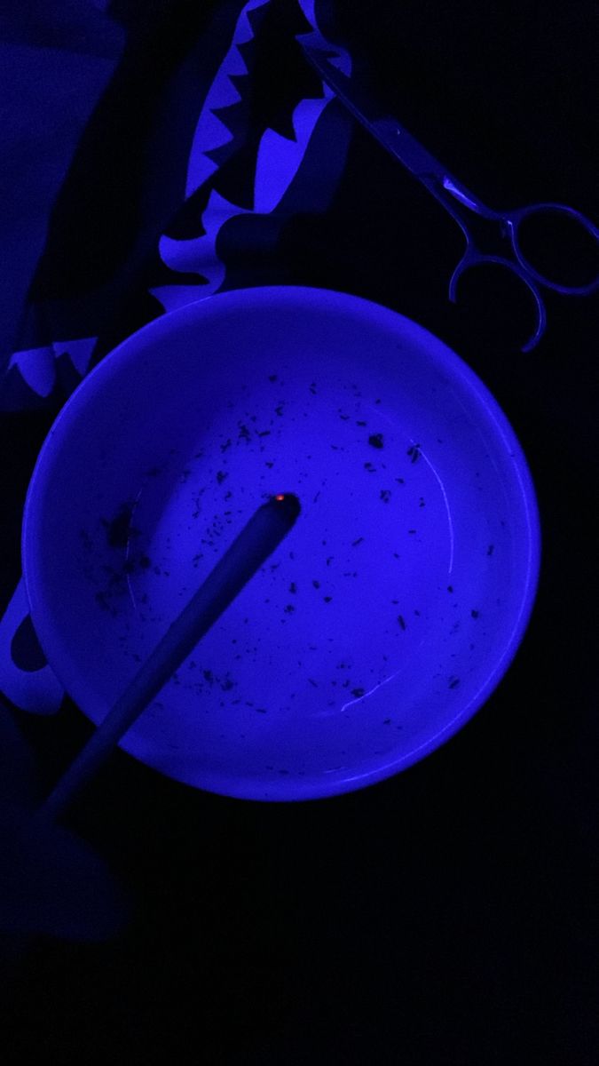 a blue bowl and pair of scissors sitting on a table in front of a dark background