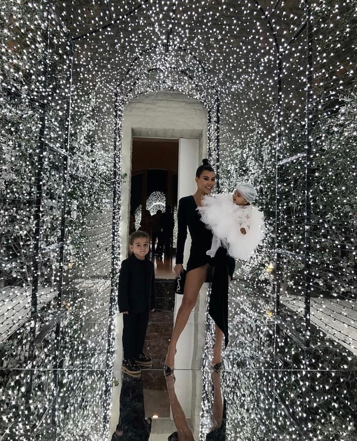 two women and a child are standing in front of christmas lights