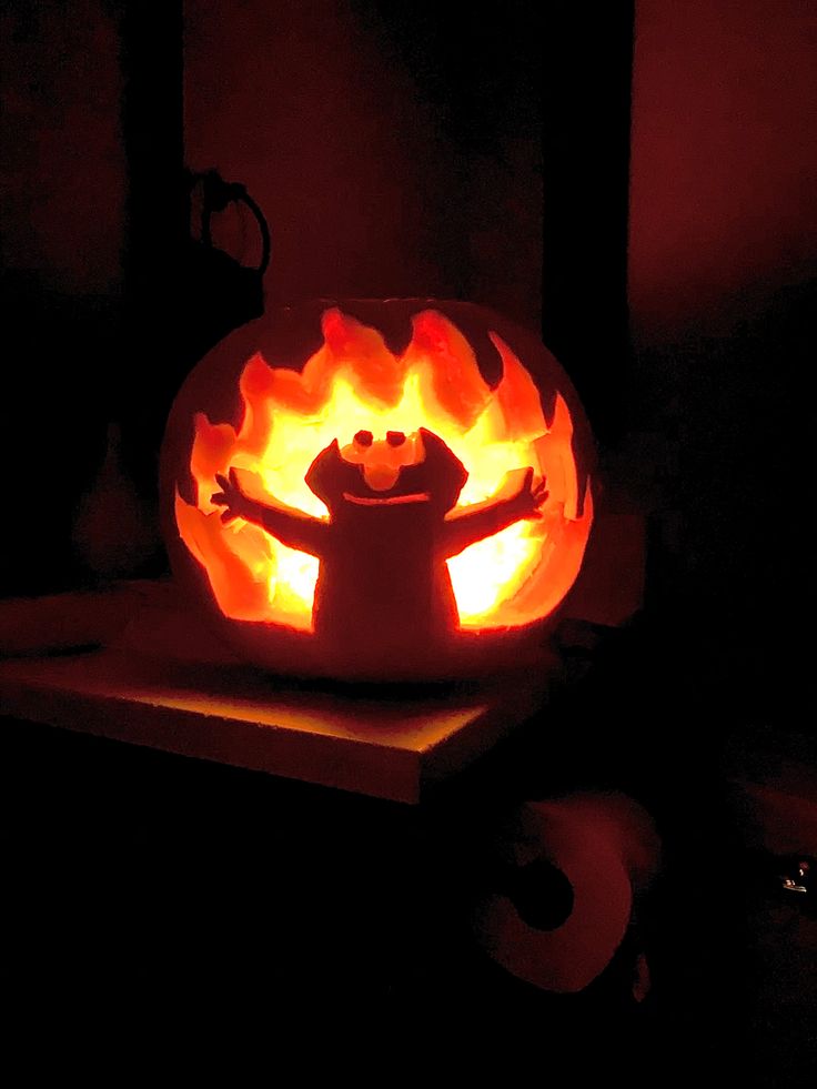 a pumpkin carved to look like a person with arms and legs in flames, sitting on a table