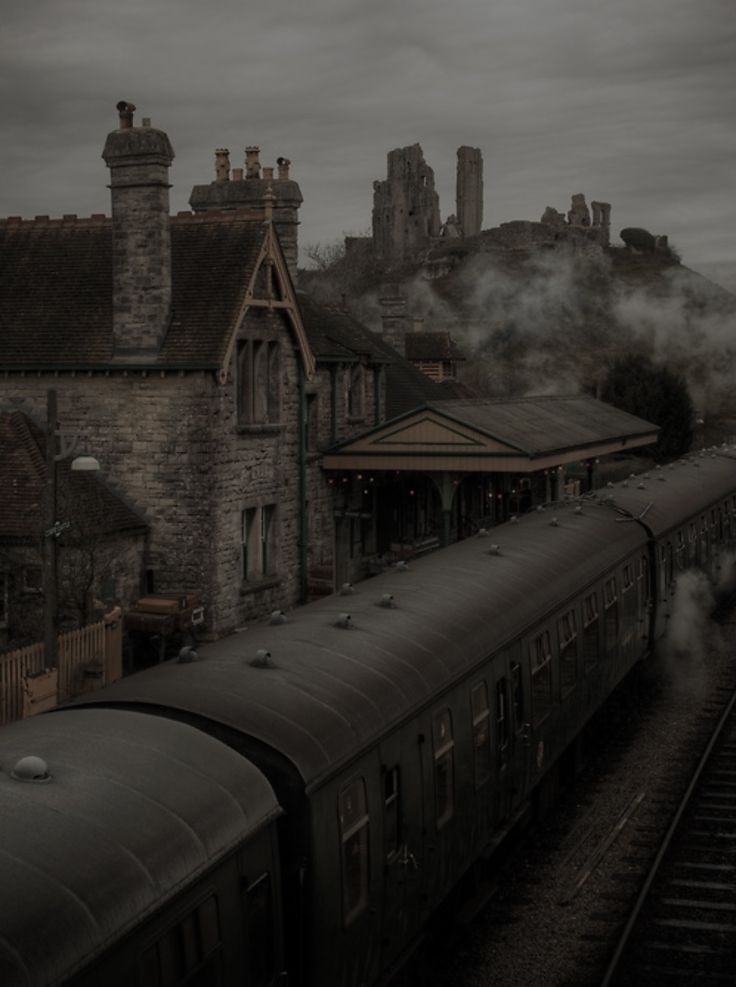 a train traveling past a tall stone building