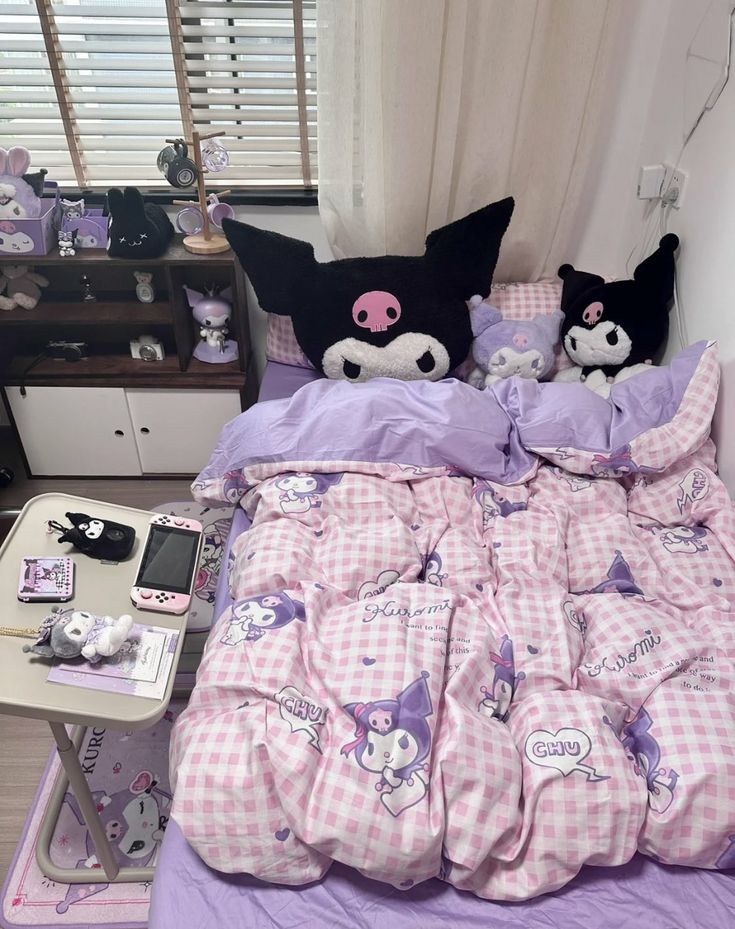 a bed with pink and white checkered sheets, pillows and other items on it