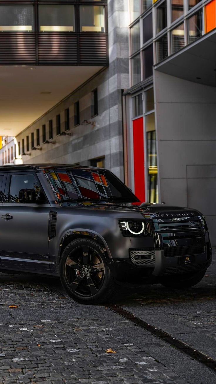 a black land rover parked in front of a building with an orange door and windows