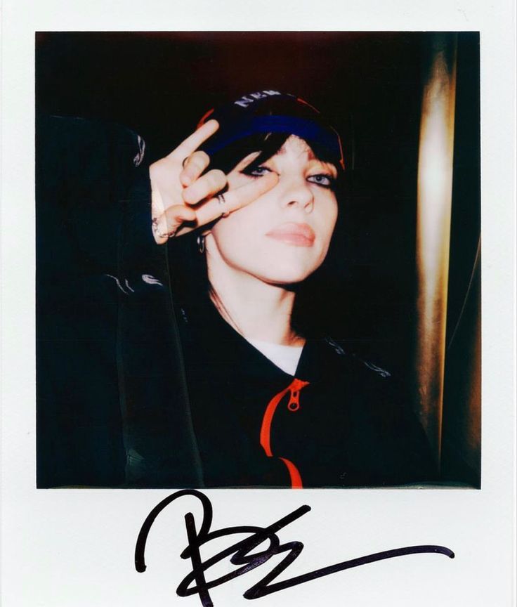 an autographed photograph of a woman with blue hair holding her hand up to her face