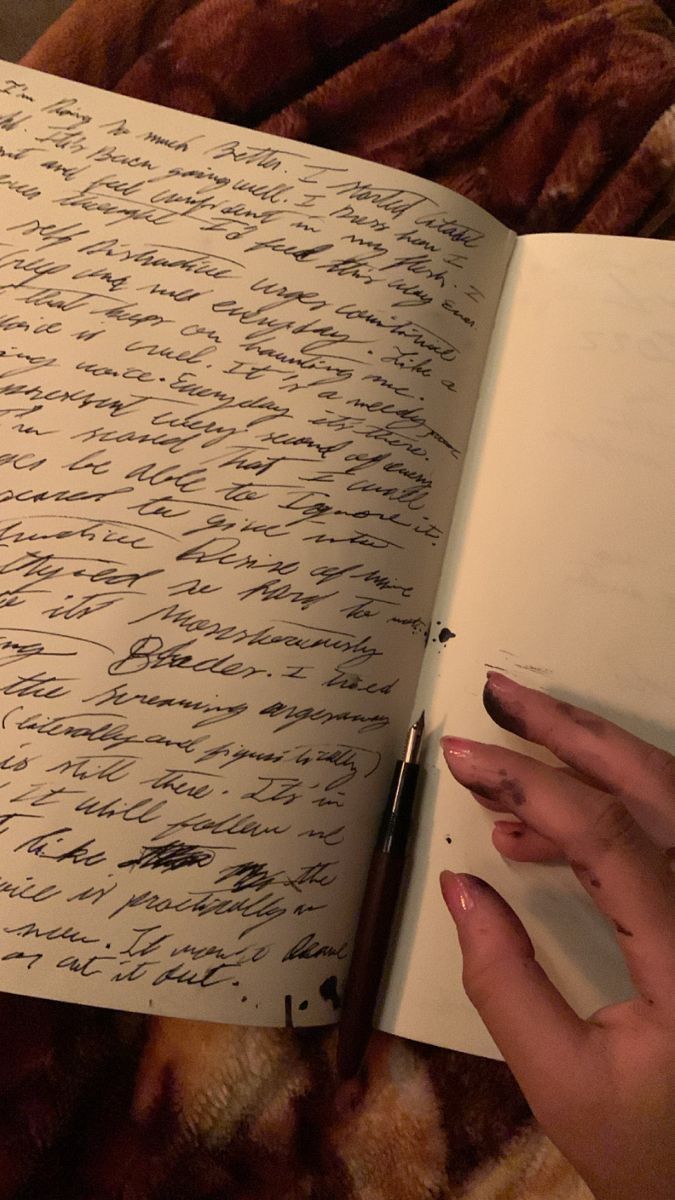 a hand is holding an open book with writing on it and a pen in the middle