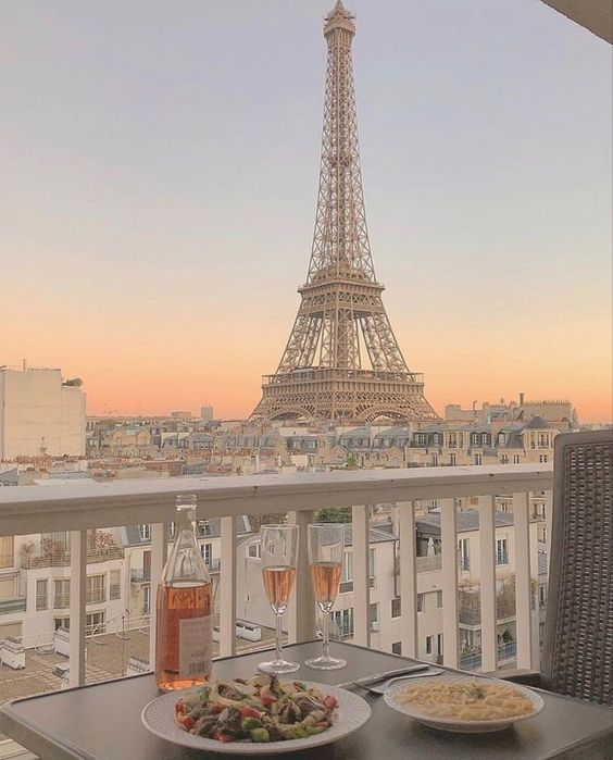 two plates of food are sitting on a table in front of the eiffel tower